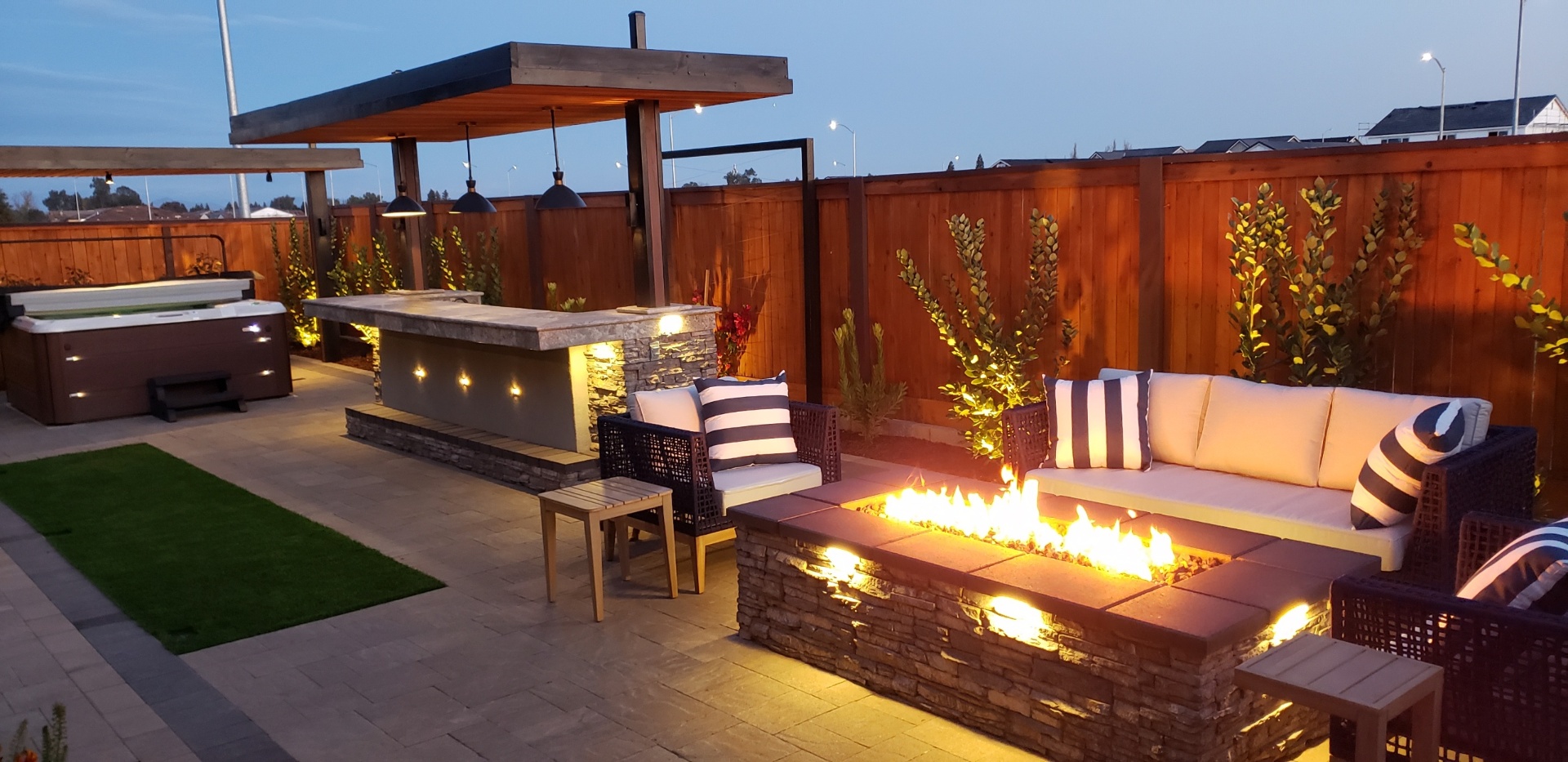 AR Landscapes — custom Fresno backyard with firepit, outdoor kitchen and pergola at dusk