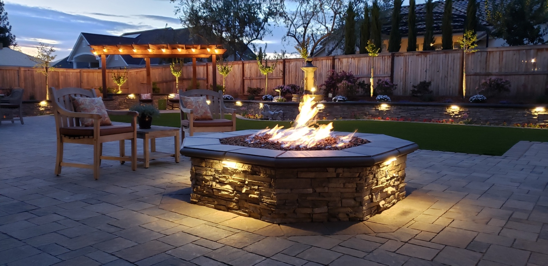 AR Landscapes — custom Fresno backyard with firepit, outdoor kitchen and pergola at dusk